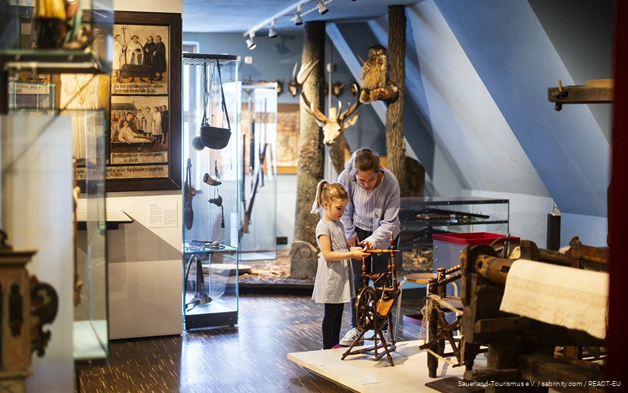 Eine Mutter und ihre Tochter betrachten eine Spindel im Südsauerlandmuseum in Attendorn.