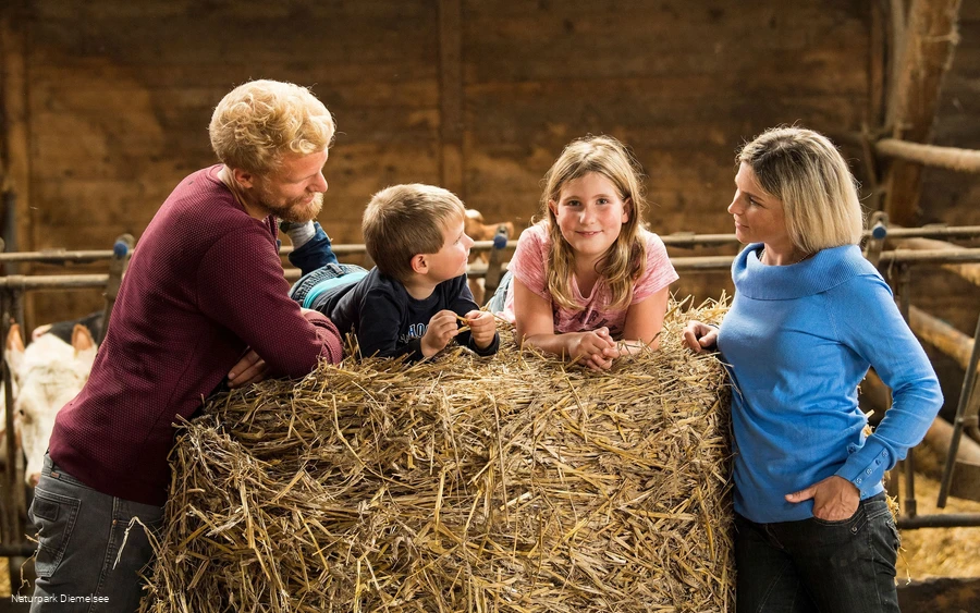Familie mit Kindern auf einem Strohballen Familienbauernhof Fass Familie mit Kindern auf einem Strohballen Familienbauernhof Fass