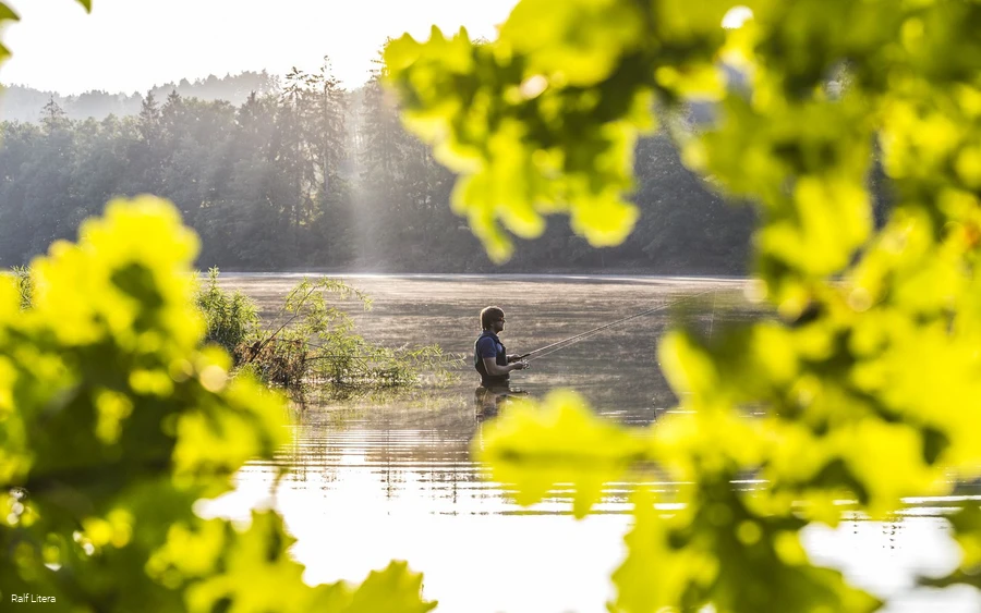 Ein Angler steht mit seiner Angel im Sorpesee.