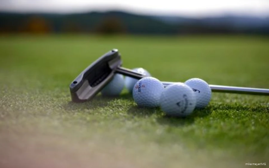 Golfschläger und Golfbälle liegen auf dem Platz.