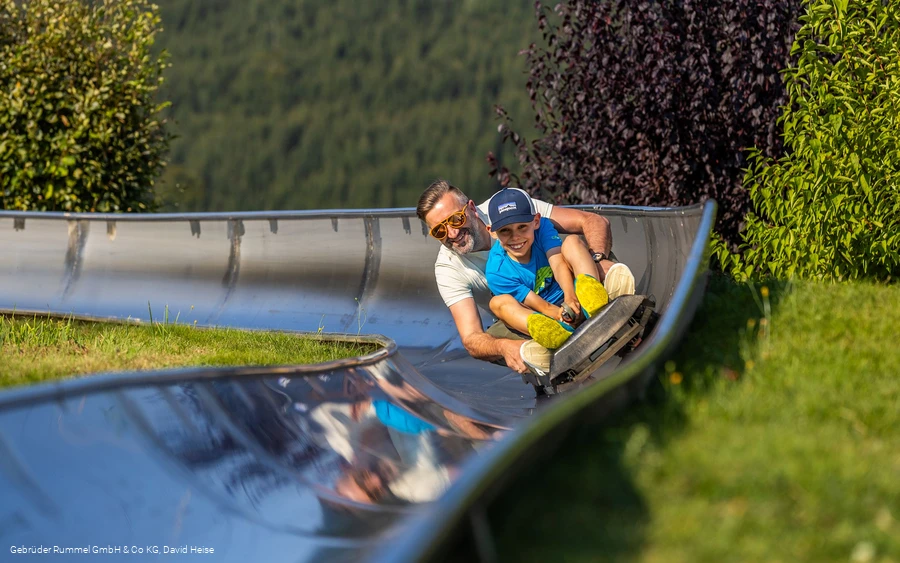Mann und Junge auf der Sommerrodelbahn