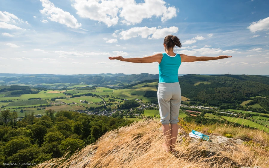 Eine Frau genießt die weite Aussicht auf den Bruchhauser Steinen