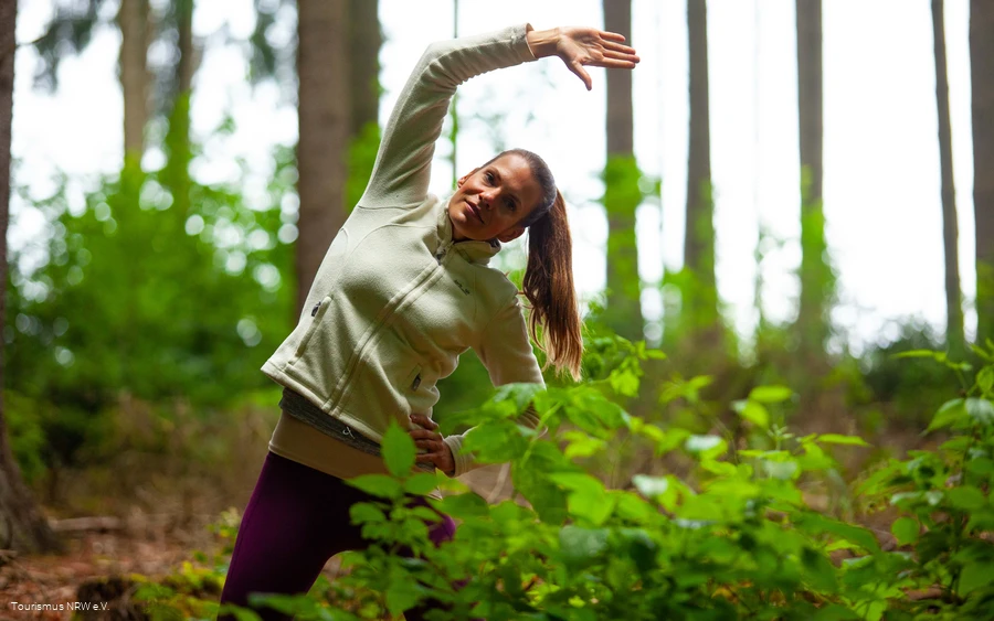 A woman does an exercise in the forest