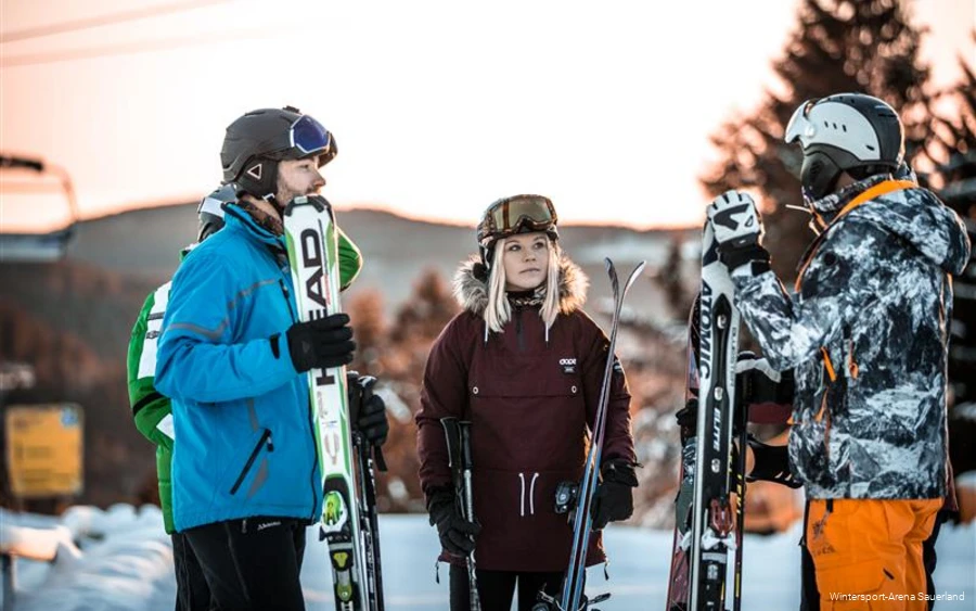 Eine Gruppe Skifahrer in voller Montur unterhält sich am Anfang einer Skipiste