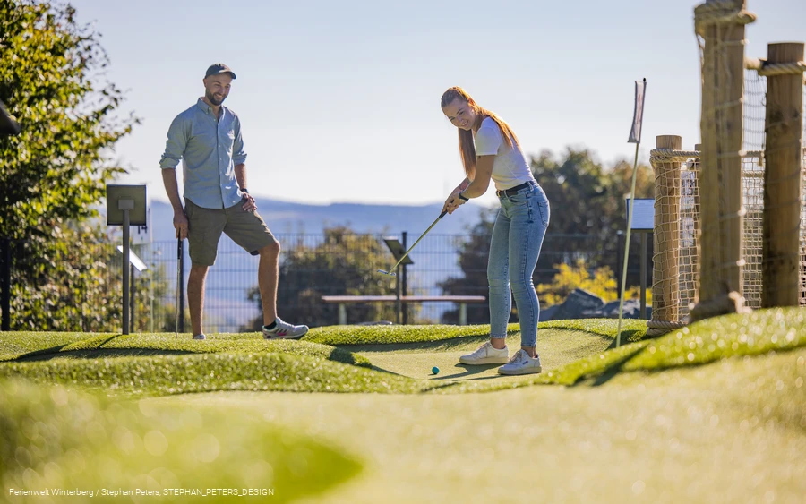Zwei Personen spielen Minigolf.