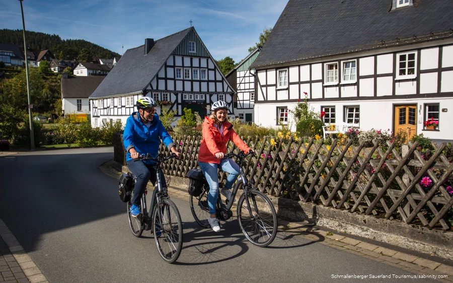 Een stel maakt een fietstocht door een vakwerkdorp.