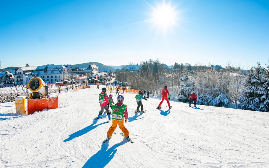 Skilehrern mit Kindern beim Skifahren üben.