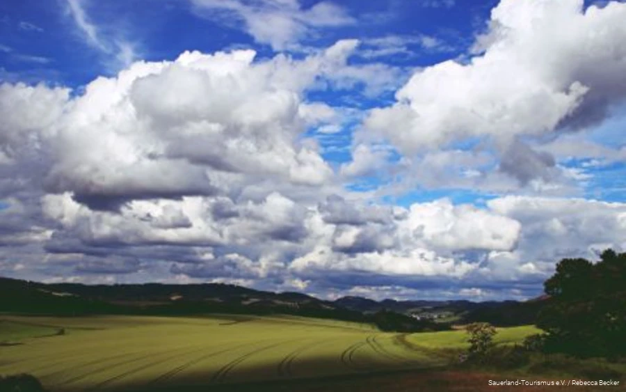 Thick clouds in the blue sky drift across the Sauerland landscape.