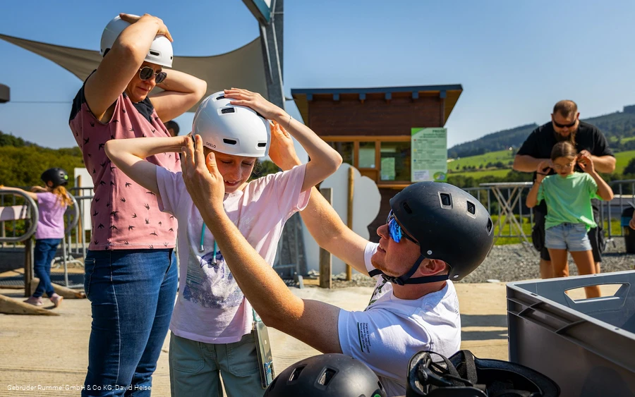 Familie setzt an der Sesselbahn Ritzhagen Helme auf für die Mountaincartstrecke 