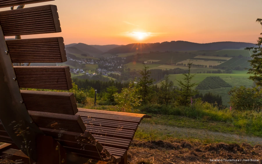 Sonnenuntergang am Hömberg mit Bank im Vordergrund.