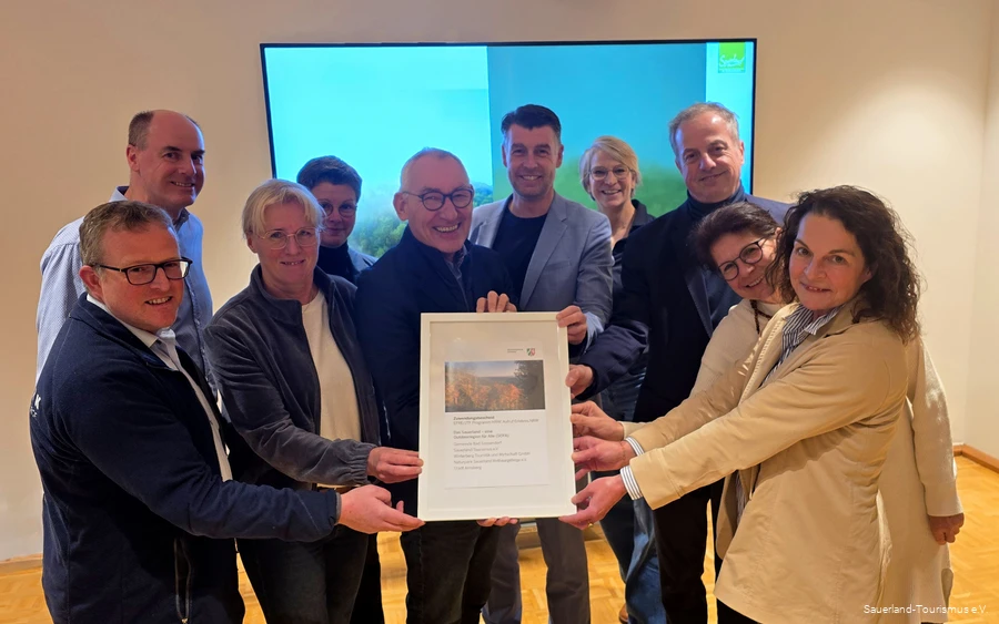 Die zehn Projektbeteiligten halten glücklich den Förderbescheid für das Barrierefreiheits-Projekt in den Händen.