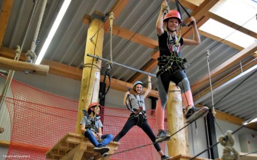 Kinder klettern im Indoor-Hochseilgarten.