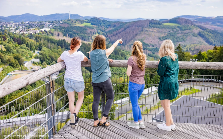 Eine Gruppe Personen genießt die Aussicht von der Panorama Erlebnisbrücke auf Winterberg.