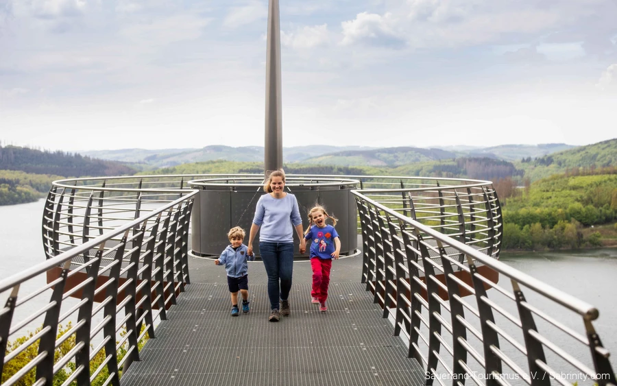 Een moeder loopt met twee kinderen aan de hand over de Skywalk Biggeblick.