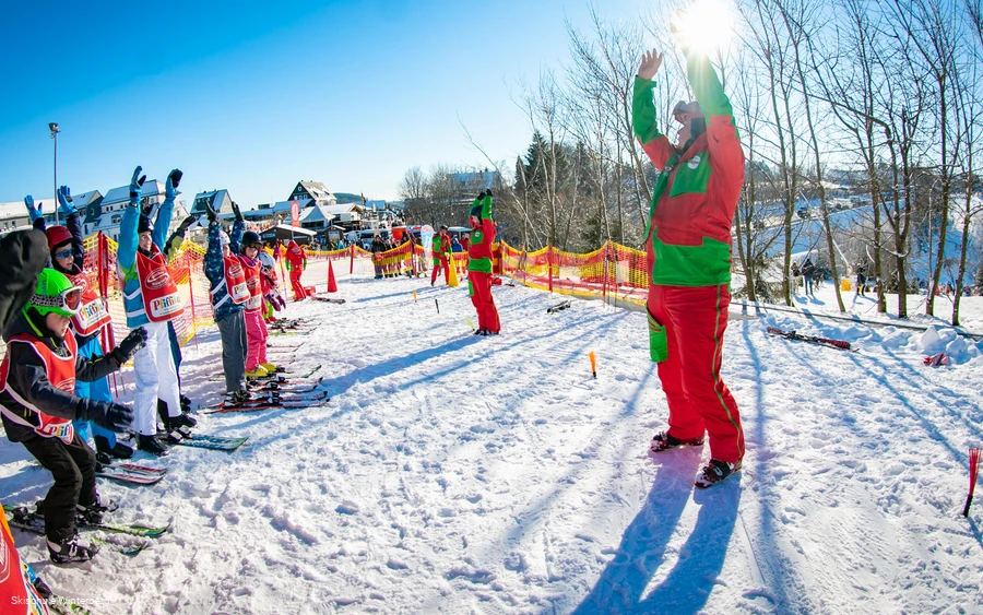 Skilehrer erklärt seinen Schülern etwas.
