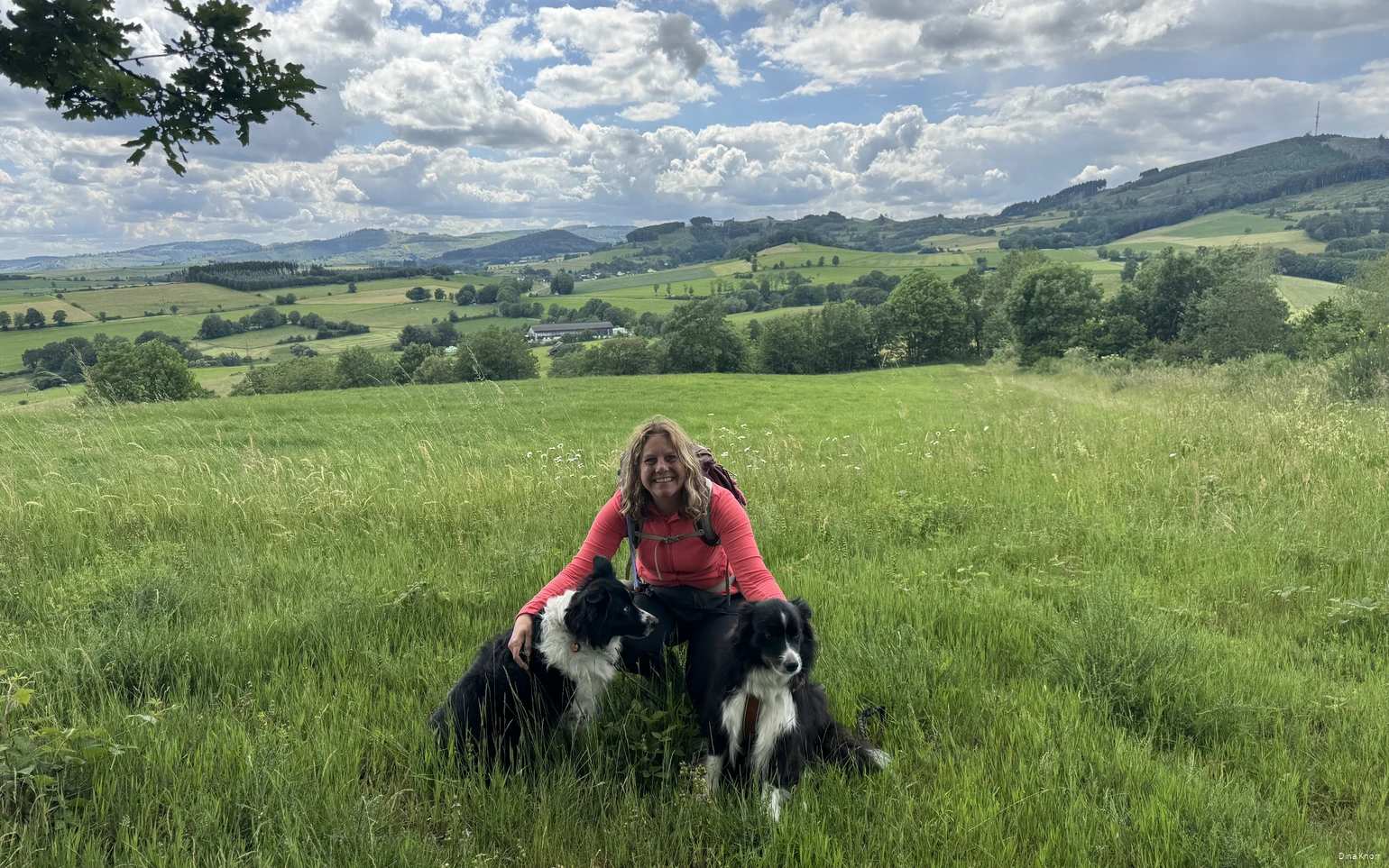 Blogger Dina Knorr poseert met haar twee honden tegen de achtergrond van het groene landschap van het Sauerland tijdens een van haar wandeltochten.