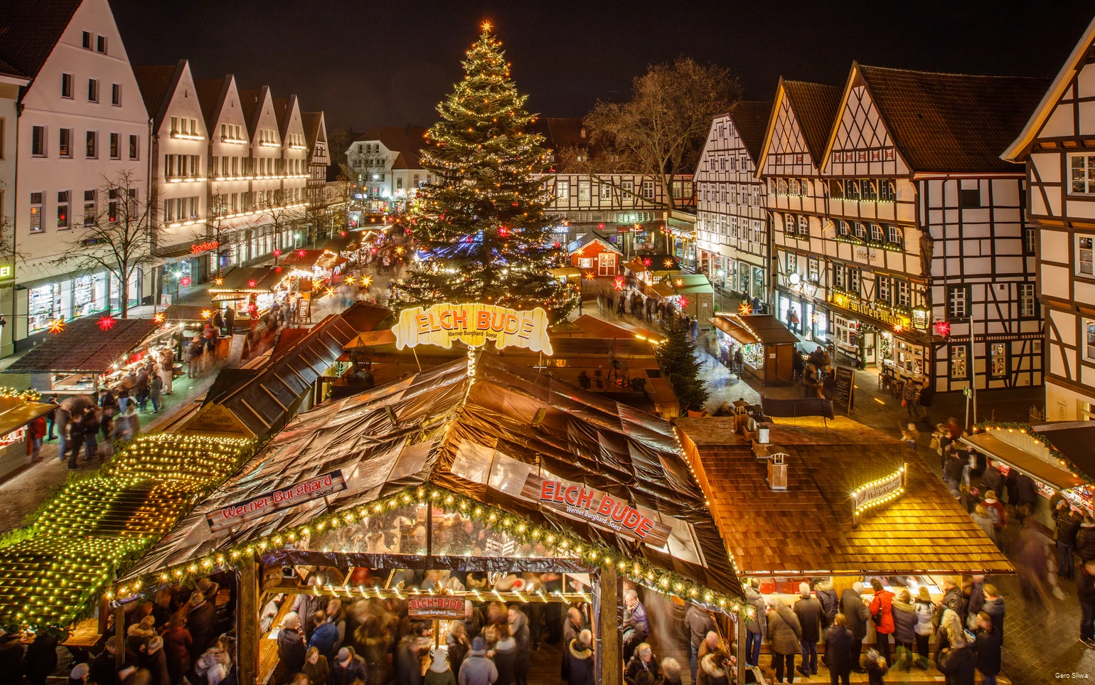 Blick von oben auf den Soester Weihnachtsmarkt mit vielen verschiedenen Buden, einem großen Weihnachtsbaum und Fachwerkhäusern.