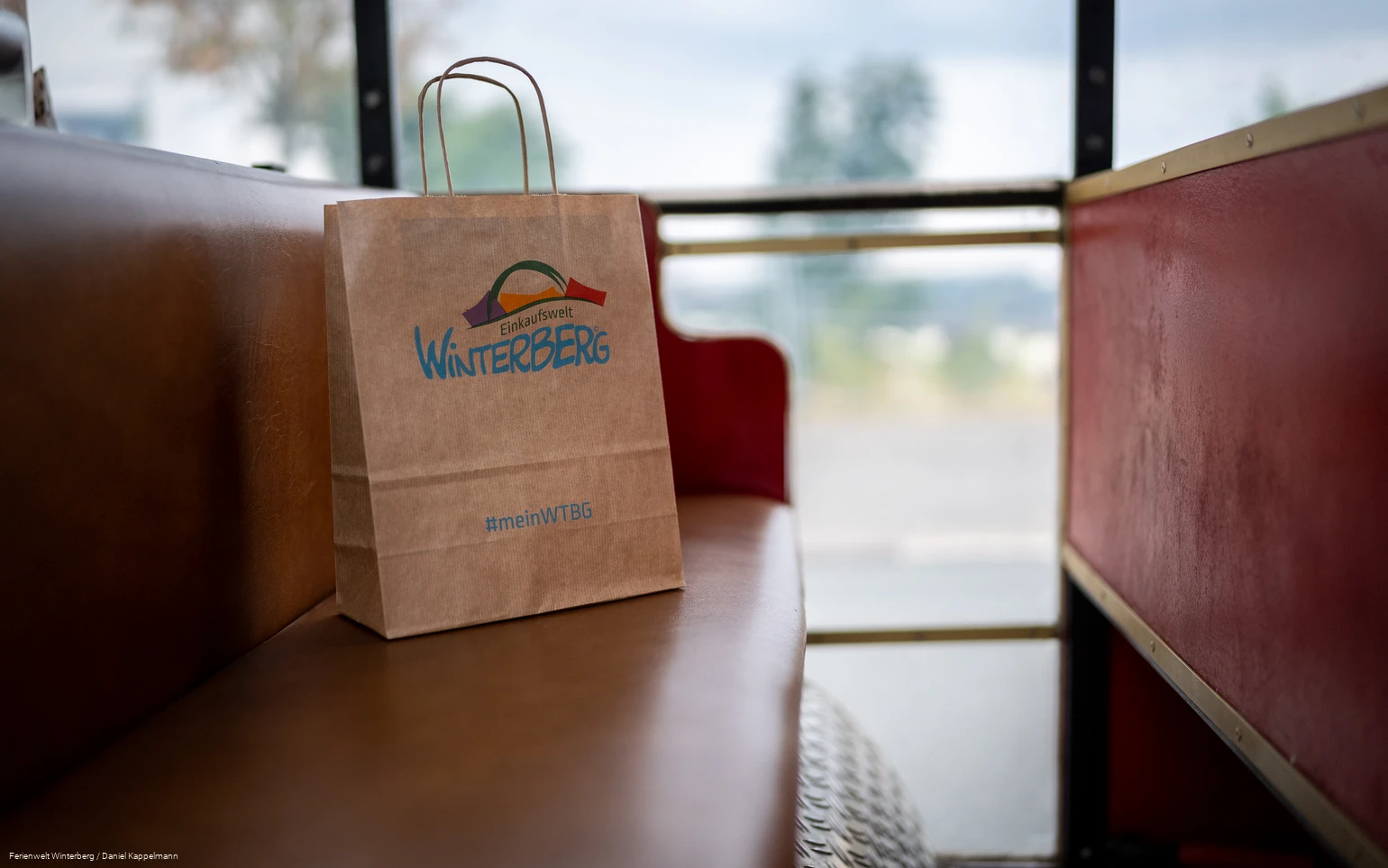 Eine Winterberger Einkaufstüte aus Papier auf einer roten Sitzbank.