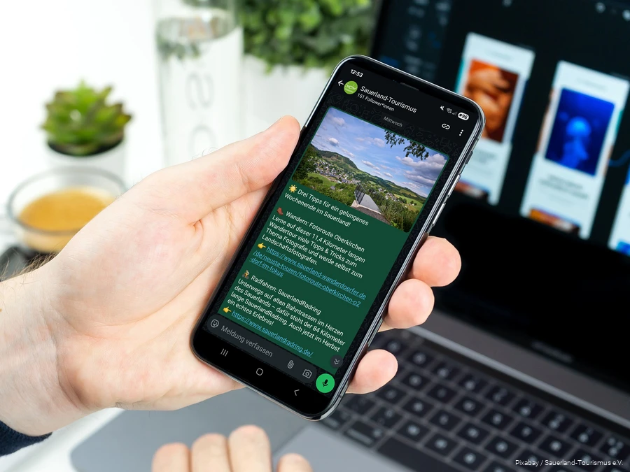 Ein Smartphone wird in der Hand gehalten. Auf dem Bildschirm sieht man einen Post im neuen WhatsApp-Kanal des Sauerland-Tourismus.