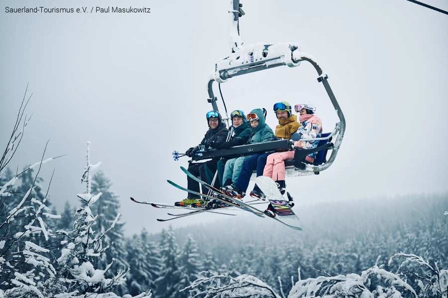 Een vrolijke groep wintersporters zit in de stoeltjeslift.
