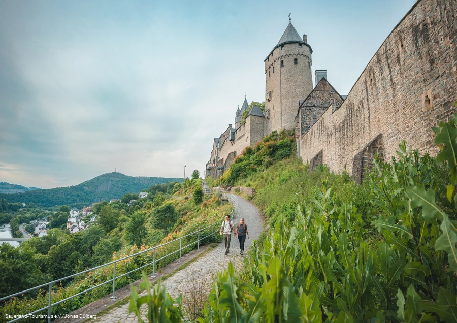 zwei Wanderer gehen unterhalb der Burg Altena