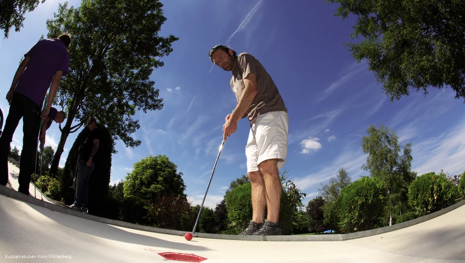 Ein Mann beim Minigolf spielen.