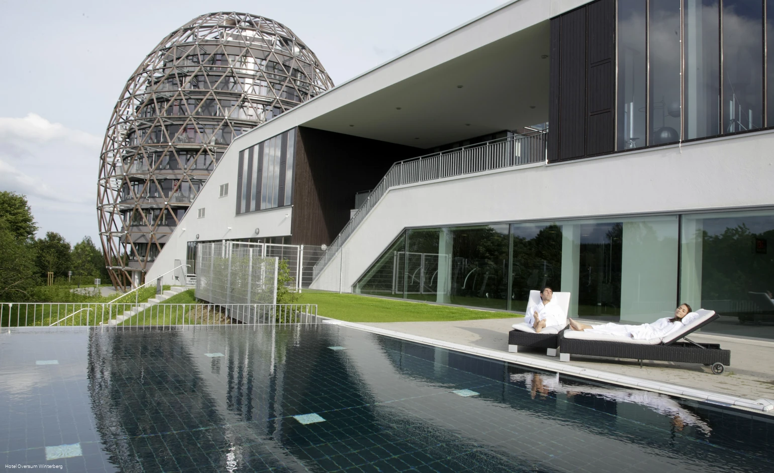 Außenansicht des Hotels Oversum mit Außenpool und Liegemöglichkeit.