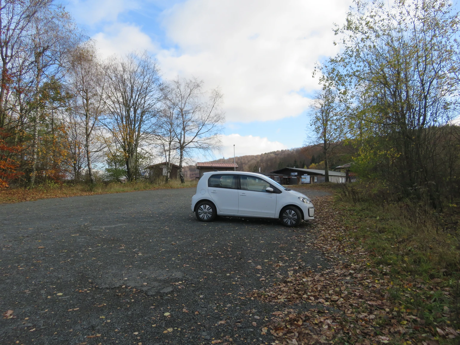 Ein kleines weißes Auto parkt auf einem Parkplatz am Wegesrand. Ein kleines weißes Auto parkt auf einem Parkplatz am Wegesrand.