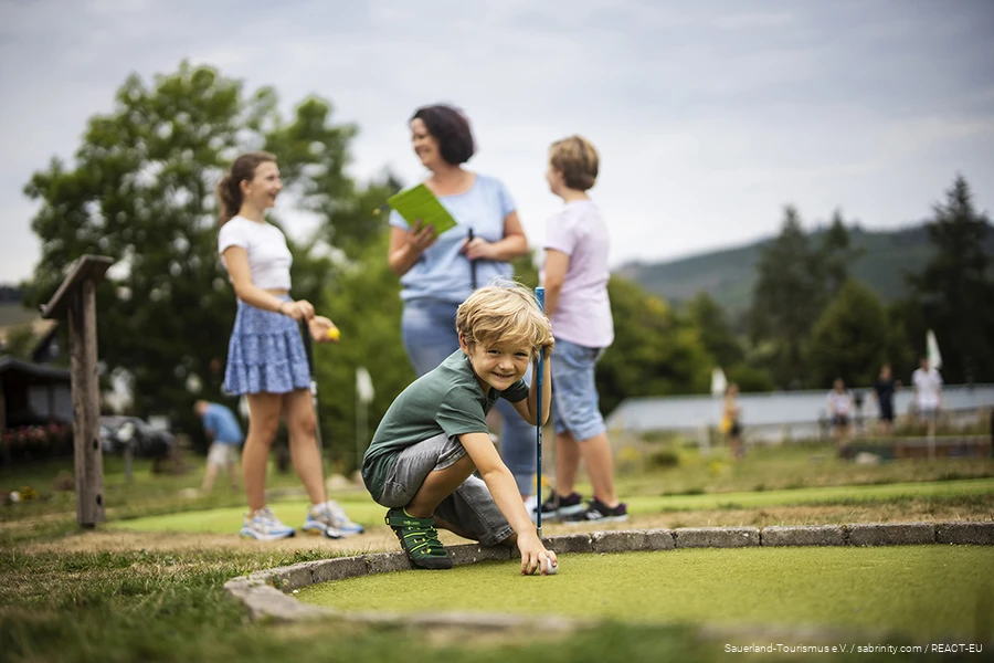 Eine Familie beim Minigolfen am Diemelsee. Ein Sohn bereitet seinen nächsten Schlag vor.