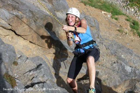 Frau klettert am Felsen.