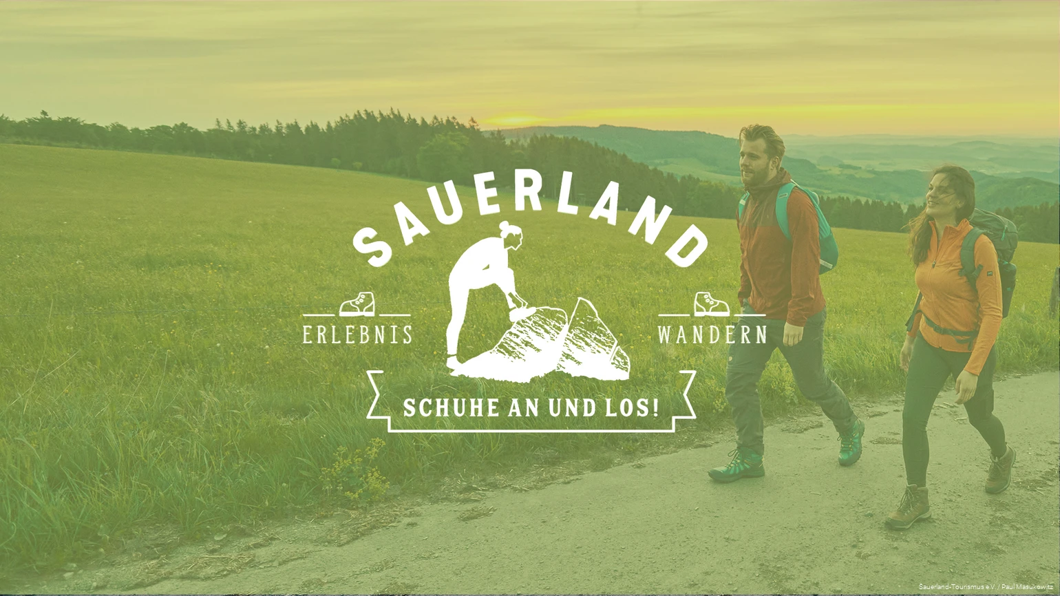 Im Hintergrund wandert ein junges Pärchen bei schöner Abendstimmung. Im Vordergrund der Schriftzug "Sauerland - Schuhe an und los!"